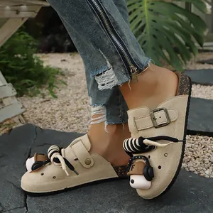 Close-up of women's beige suede clog slippers with decorative charms and cork sole.