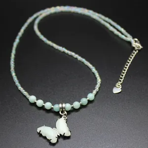 Macro detail view of a butterfly pendant necklace featuring mint green and iridescent beads