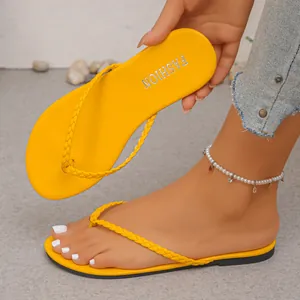 Detailed view of bright yellow flat thong sandals with stylish braided straps for summer
