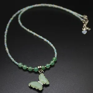 Macro detail of a green natural stone butterfly pendant on an elegant beaded necklace