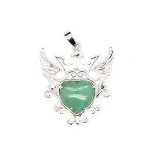 Detalle de un colgante de corazón plateado con gema verde, corona y alas elegantes