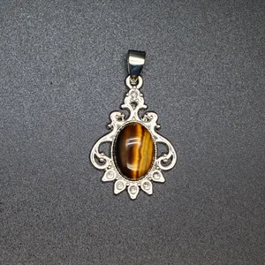 Close-up macro view of vintage silver filigree pendant with oval brown tiger eye stone