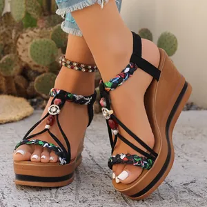 Gros plan de sandales compensées bohèmes avec brides tressées et accents de perles colorées.