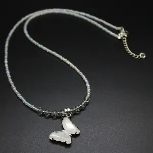 Detail view of a luxury butterfly pendant necklace with iridescent beads and white stone wings.