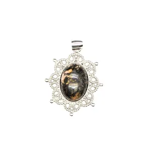 Detailed macro view of an oval natural stone pendant with silver hollow lace filigree