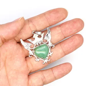 Detalle de un colgante de corazón de piedra natural verde con corona y alas plateadas