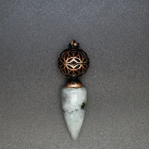 Dettaglio di un ciondolo in pietra naturale conica con una sfera di bronzo traforata.
