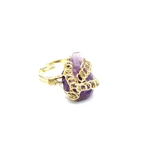 Dettaglio ravvicinato di un anello in filo dorato fatto a mano con ametista viola grezza