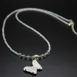 Detailed macro view of a white crystal butterfly pendant necklace with iridescent beads.
