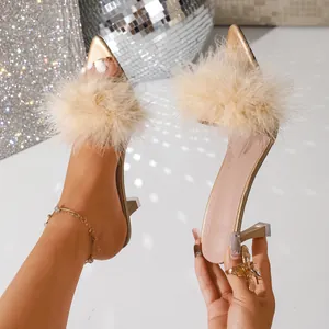 Dettaglio di eleganti sabot in oro champagne con piume e tacco a spillo per feste e cerimonie