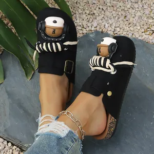 Detail of black closed-toe clogs with cute bear charm and decorative rope accents.