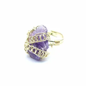 Vista dettagliata di un anello in ametista grezza fatto a mano con avvolgimento in filo dorato