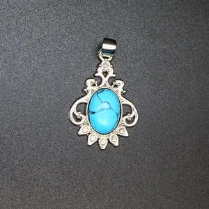 Close-up detail of a vintage silver pendant featuring an oval blue turquoise stone