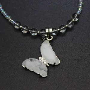 Macro view of a natural white stone butterfly pendant on an iridescent beaded necklace