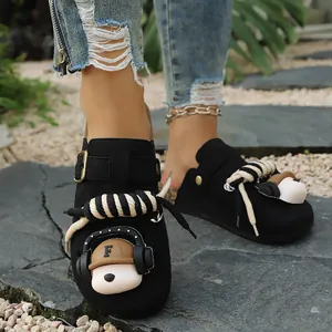 Detailed view of black platform clogs featuring a cute teddy bear charm and rope accent.