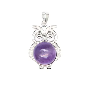 Dettaglio frontale di un ciondolo a forma di gufo in argento con pietra viola tonda.