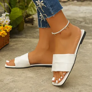 Elegant white square toe flat slides shown on feet with a decorative pearl anklet accessory