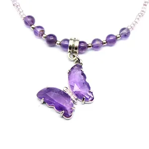 Macro view of a faceted purple amethyst butterfly pendant on a beaded crystal necklace.