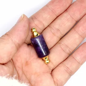 Hand-held close-up of a purple crystal cylindrical essential oil bottle pendant