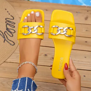 Close-up detail of yellow flat slide sandals with stylish silver chain and square toe design