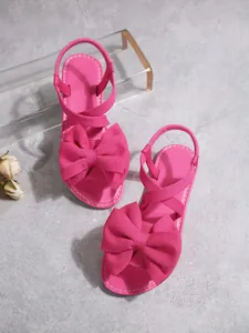 Detaillierte Draufsicht auf leuchtend rosa flache Sandalen mit großer dekorativer Schleife