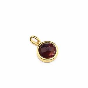Macro view of a faceted maroon natural stone pendant in a gold-plated metal bezel