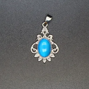 Vintage silver pendant with oval turquoise blue stone and intricate filigree design.