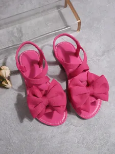 Detailansicht der leuchtend pinken offenen flachen Sandalen mit großer Zierschleife.