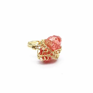 Dettaglio anello artigianale in filo d'oro con pietra di cristallo grezzo rosso anguria