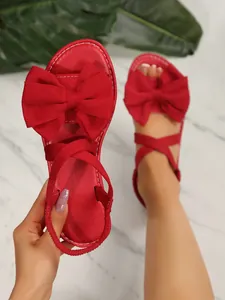 Nahaufnahme der roten flachen Sandalen mit großer Schleife und elastischem Fersenriemen