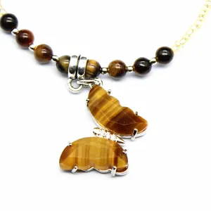 Detailed macro view of a natural tiger eye butterfly pendant with crystal accents.