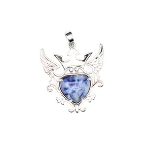 Detalle de colgante de piedra natural azul en forma de corazón con corona y alas.