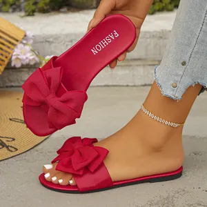 Dettaglio di ciabatte rosse basse con un grande fiocco elegante e plantare alla moda