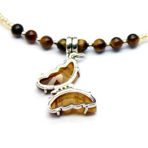 Close-up detail of a tiger's eye butterfly pendant on a beaded gemstone necklace