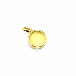 Detailed macro view of a small circular gold pendant with a faceted yellow gemstone.