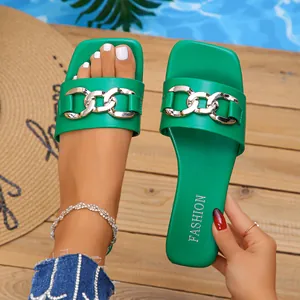 Macro detail of vibrant green square-toe flat sandals featuring a stylish gold chain decoration