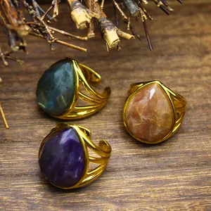 Detailed view of three teardrop crystal rings with amethyst and labradorite on wood