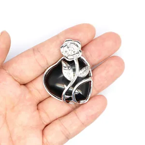 Gros plan d'un pendentif en pierre naturelle noire en forme de cœur avec une rose argentée