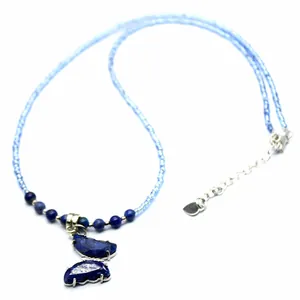 Close-up detail of a blue butterfly pendant made of semi-precious stones on a beaded chain.
