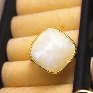 Primer plano de un anillo ajustable dorado con piedra de luna natural cuadrada facetada.