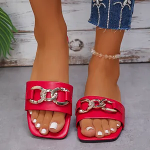 Red square toe flat sandals for women featuring chunky gold chain decoration on feet.