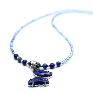Macro view of a handcrafted blue gemstone butterfly pendant on a delicate beaded chain
