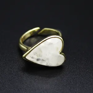 Close-up of a heart-shaped natural stone ring with a gold band on a dark background