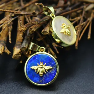 Goldener Bienenanhänger mit Lapislazuli und Perlmutt vor natürlichem Hintergrund