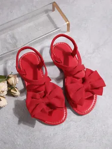 Detailansicht der leuchtend roten Schleife auf modischen flachen Sandalen für Damen