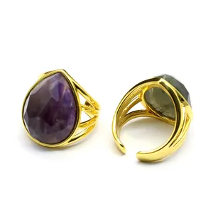 Detailed view of two adjustable gold-plated rings with faceted teardrop crystal gemstones.