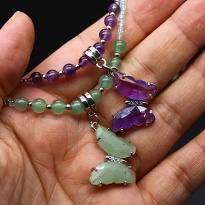 Close-up of natural amethyst and green stone butterfly pendants on beaded necklaces.