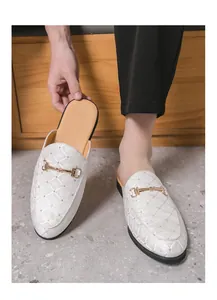Detailed view of white men's backless loafers featuring diamond pattern and golden horsebit.