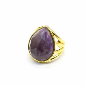 Detailed view of a gold-plated ring featuring a large faceted purple teardrop crystal