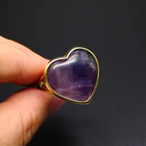 Primer plano de un anillo de corazón dorado con una piedra natural de amatista púrpura